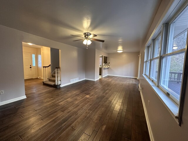 unfurnished living room with dark wood-style floors, visible vents, a fireplace, and ceiling fan