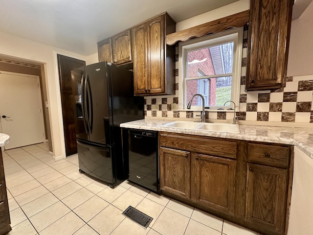 kitchen featuring light countertops, visible vents, a sink, and black appliances