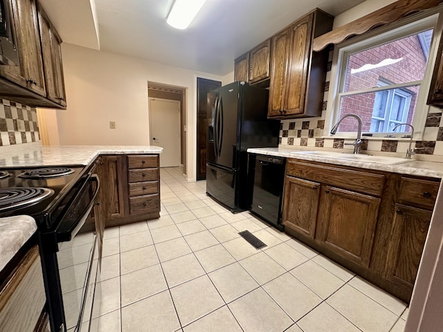 kitchen featuring light tile patterned floors, a sink, light countertops, black appliances, and tasteful backsplash