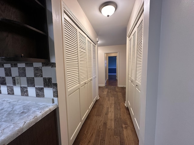 corridor with dark wood-style floors and baseboards