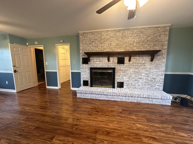 unfurnished living room featuring ceiling fan, a fireplace, baseboards, and wood finished floors