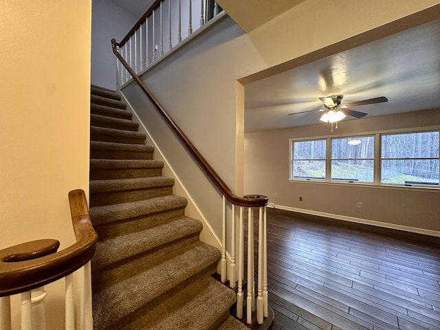 stairway with ceiling fan, baseboards, and wood finished floors