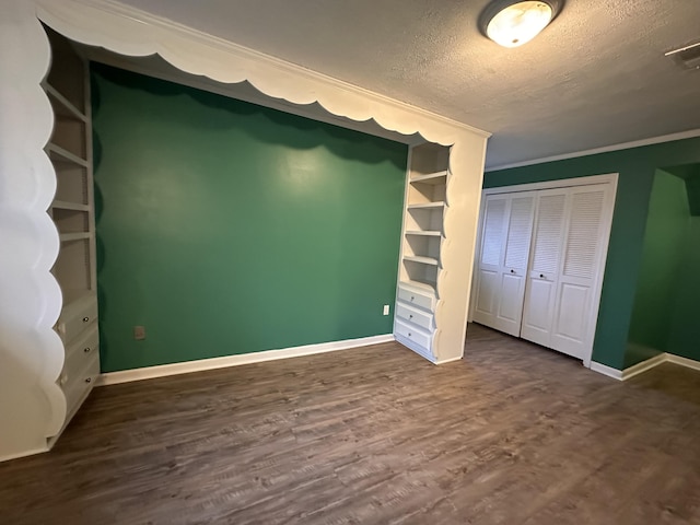 unfurnished bedroom featuring a textured ceiling, baseboards, and dark wood-style flooring