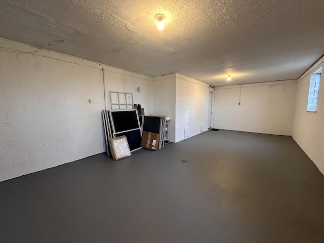 interior space featuring concrete block wall, a textured ceiling, and concrete flooring