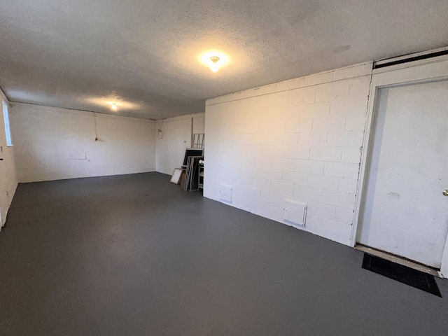 finished basement with a textured ceiling and concrete block wall