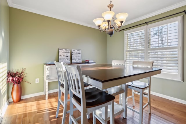 dining area with ornamental molding, a notable chandelier, baseboards, and wood finished floors