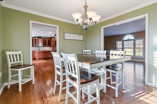 dining area with an inviting chandelier, crown molding, and wood finished floors