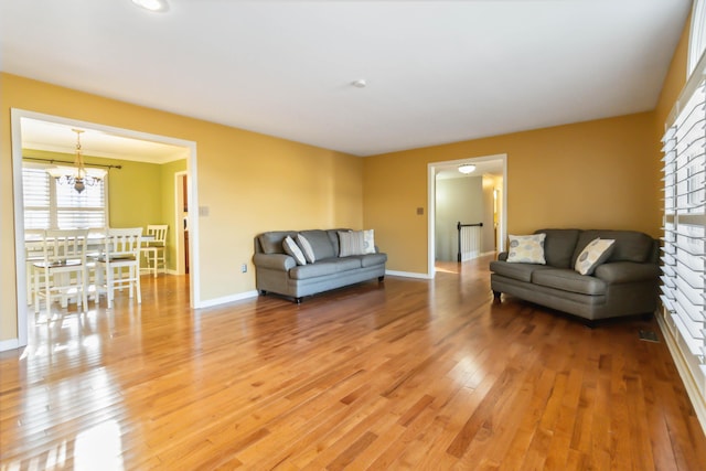 living room featuring light wood-style floors, a notable chandelier, and baseboards