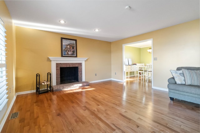 living area with baseboards, a fireplace, visible vents, and wood finished floors