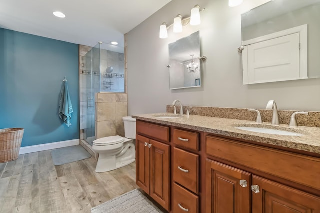 full bath featuring a stall shower, a sink, toilet, and wood finished floors