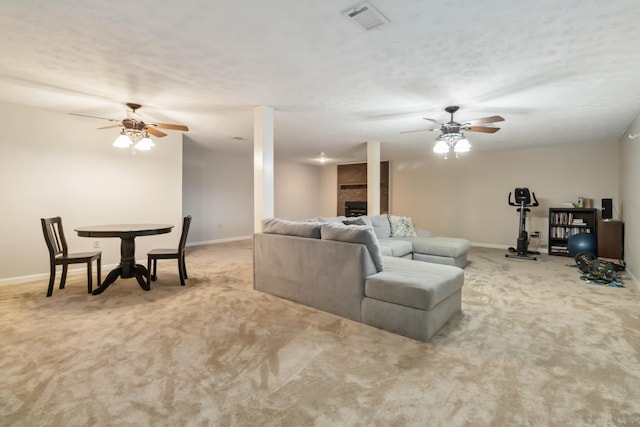 carpeted living room with a ceiling fan, a fireplace, visible vents, and baseboards