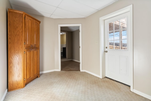 interior space featuring a paneled ceiling and baseboards