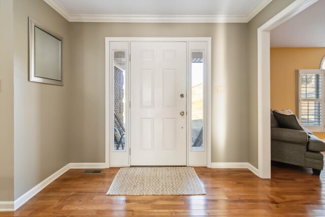 foyer with wood-type flooring, crown molding, and baseboards