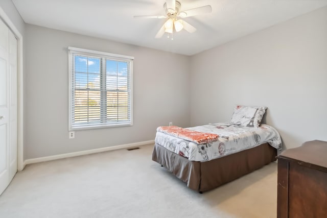 bedroom with a closet, light colored carpet, visible vents, ceiling fan, and baseboards