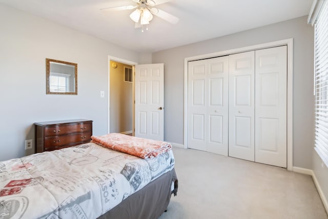 bedroom featuring light carpet, ceiling fan, baseboards, and a closet