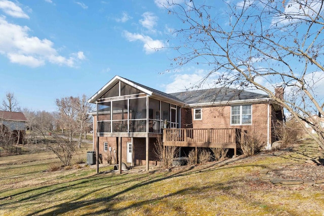 rear view of property with a sunroom, a chimney, a yard, central air condition unit, and brick siding