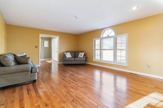 living room with light wood-style floors, visible vents, and baseboards