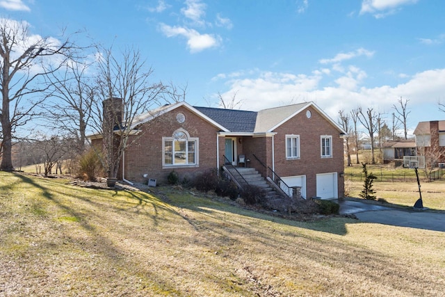 single story home with brick siding, concrete driveway, a chimney, an attached garage, and a front yard