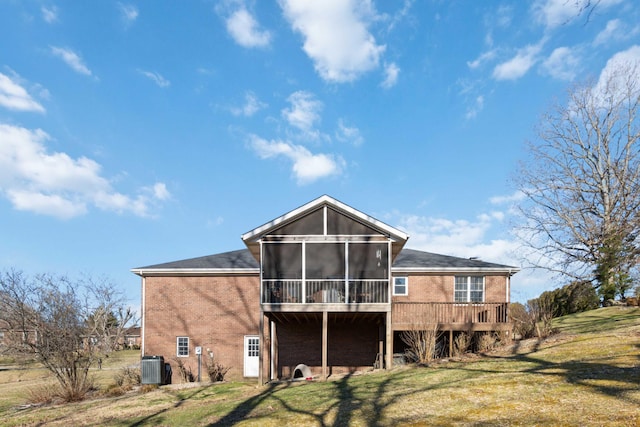 rear view of house with brick siding, a lawn, cooling unit, and a sunroom