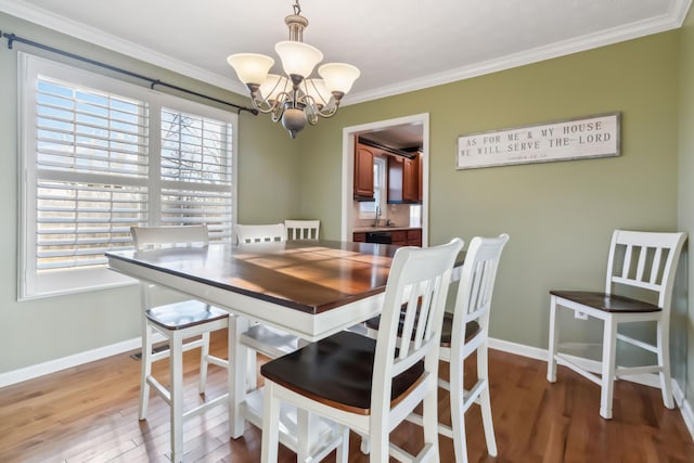 dining space featuring baseboards, ornamental molding, light wood-style flooring, and an inviting chandelier