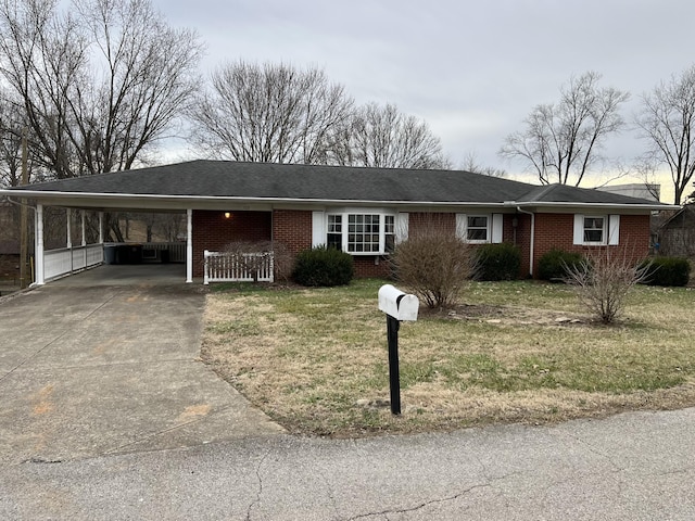 single story home featuring concrete driveway, brick siding, a front lawn, and an attached carport