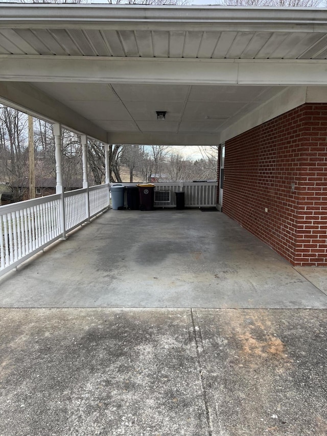 view of vehicle parking with concrete driveway, a carport, and fence