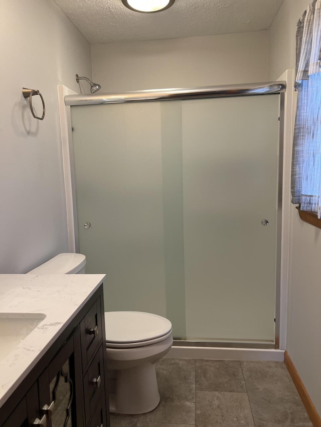 full bath featuring a textured ceiling, toilet, vanity, baseboards, and a shower stall