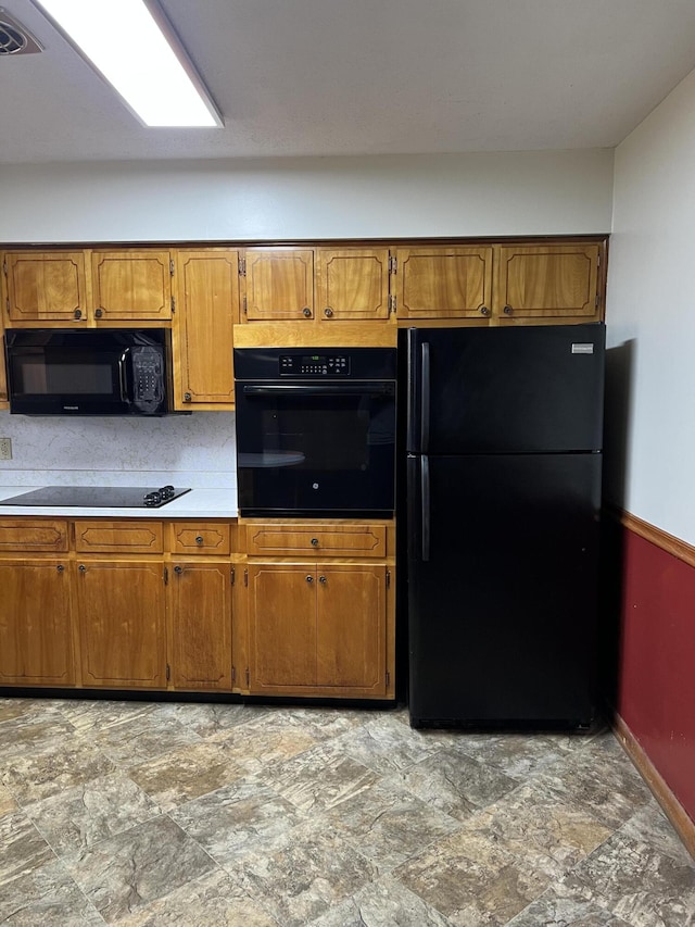 kitchen featuring black appliances, brown cabinetry, and light countertops