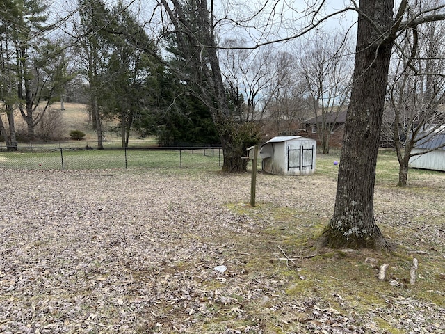 view of yard featuring a storage shed, fence, and an outbuilding