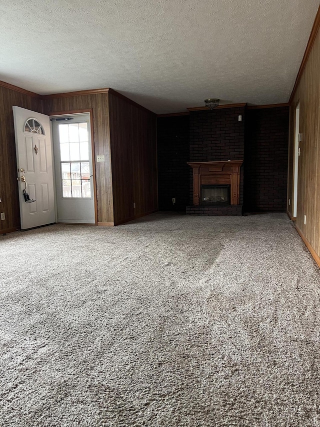 unfurnished living room featuring ornamental molding, a fireplace, wood walls, and carpet flooring