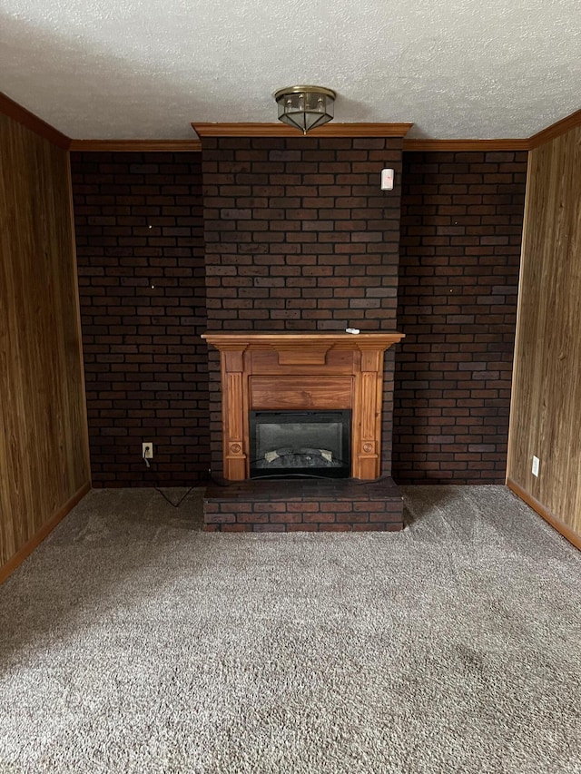 unfurnished living room with carpet floors, wooden walls, a fireplace, and a textured ceiling