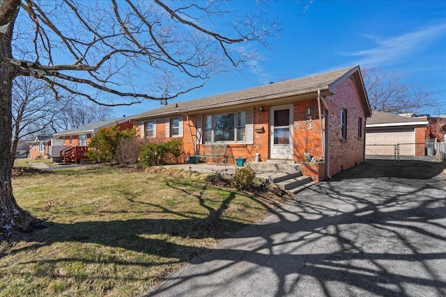 ranch-style house featuring an outbuilding, brick siding, a front yard, and a garage