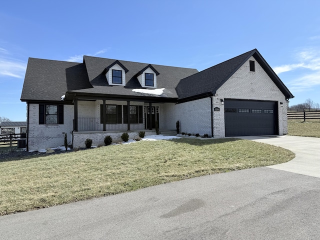 view of front of home featuring a front yard, covered porch, brick siding, and fence