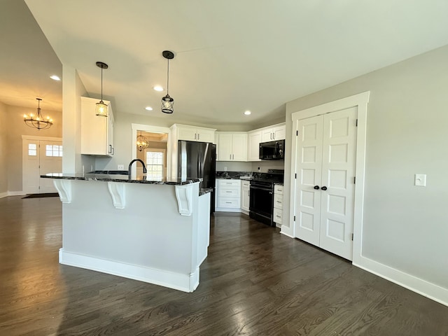 kitchen featuring dark wood-style flooring, baseboards, black appliances, a peninsula, and a kitchen breakfast bar