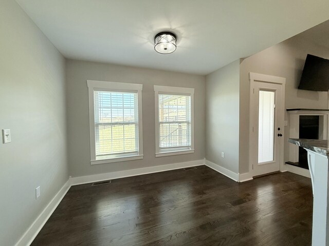 unfurnished dining area featuring dark wood-style floors, visible vents, and baseboards