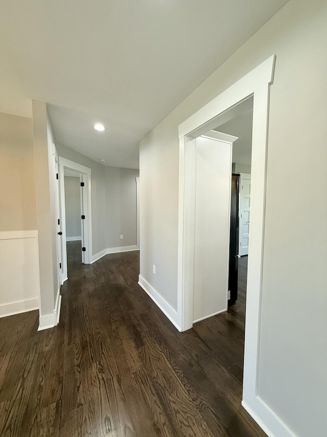 hallway featuring recessed lighting, dark wood finished floors, and baseboards