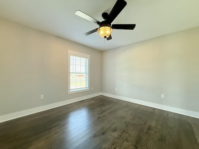 spare room with dark wood-style floors, visible vents, baseboards, and a ceiling fan