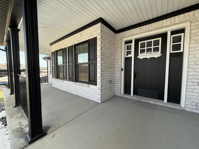 doorway to property with covered porch and brick siding