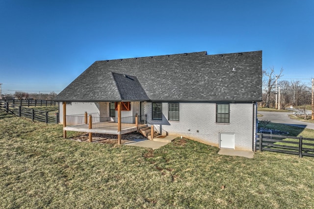 back of house featuring a yard, brick siding, and roof with shingles