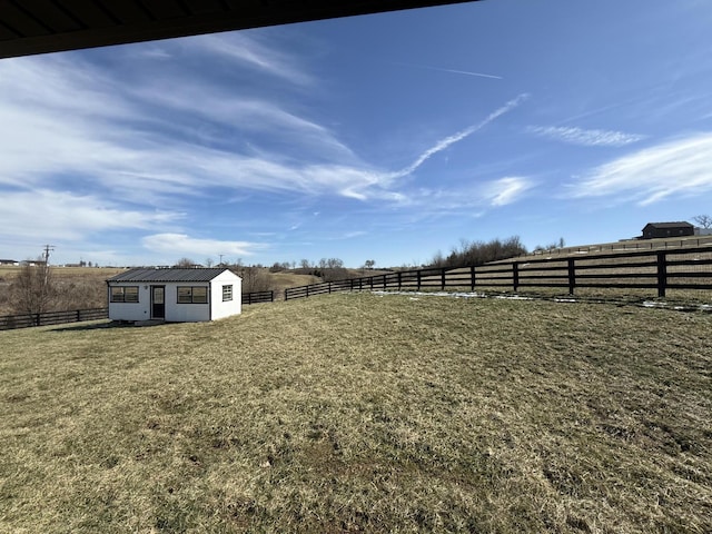 view of yard with an outbuilding, a rural view, and fence