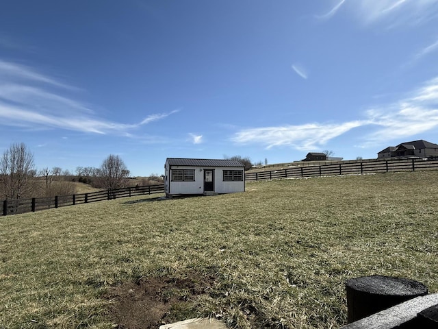 view of yard with a rural view, an outdoor structure, and fence