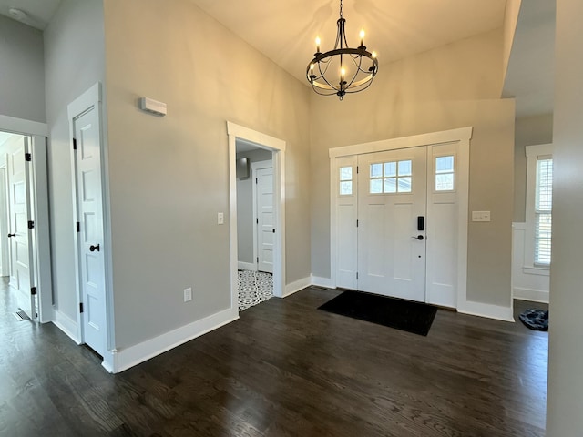 entrance foyer with a towering ceiling, baseboards, and dark wood-type flooring