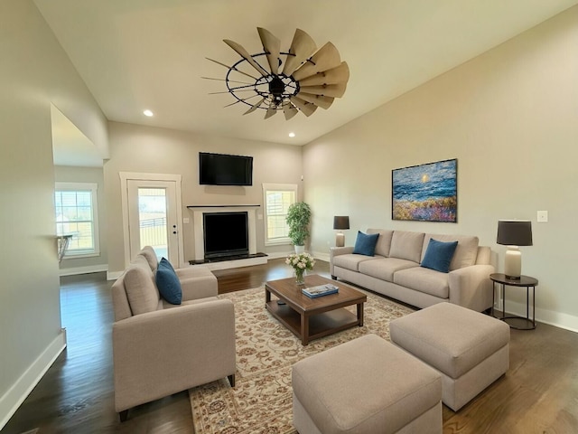 living room with dark wood-style floors, a fireplace with raised hearth, recessed lighting, and baseboards