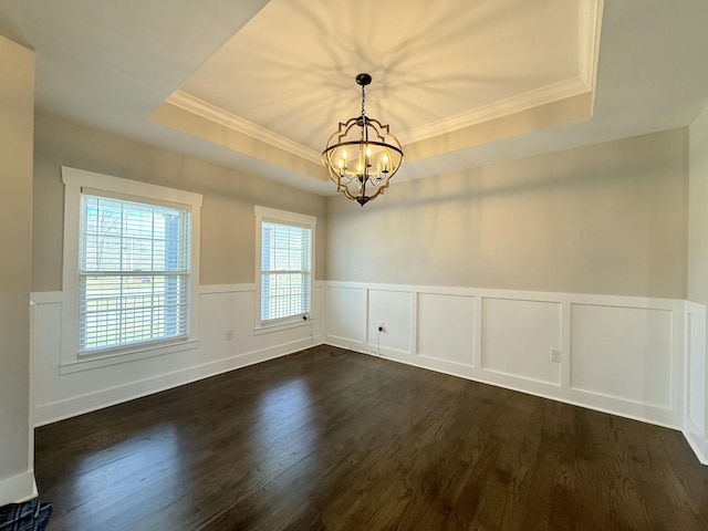 spare room featuring a notable chandelier, crown molding, a raised ceiling, and dark wood-style flooring