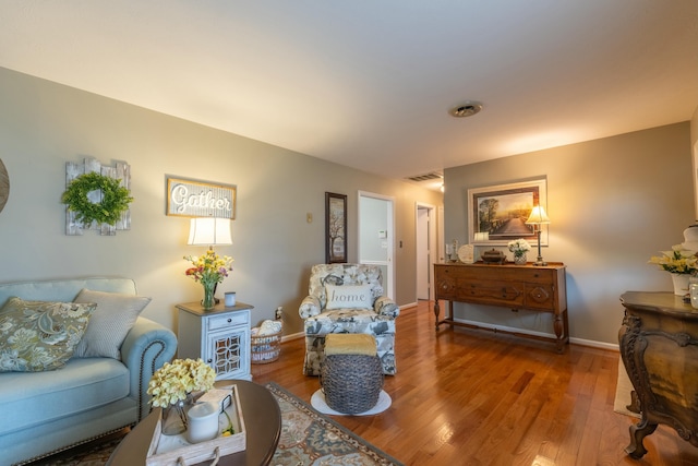 living area with baseboards, visible vents, and wood finished floors