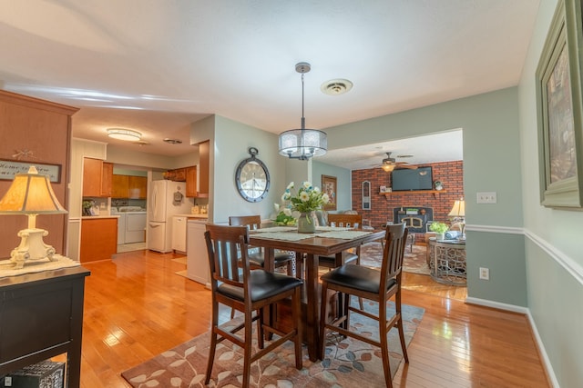 dining area featuring visible vents, baseboards, light wood-style flooring, ceiling fan, and washing machine and dryer