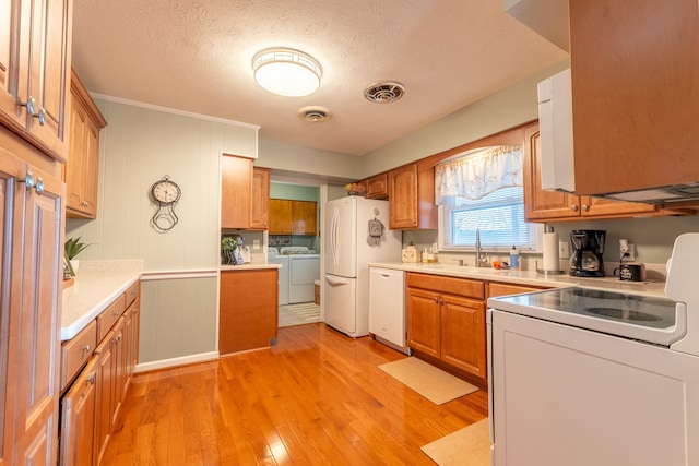 kitchen featuring white appliances, a sink, visible vents, light countertops, and washing machine and clothes dryer