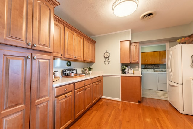 kitchen featuring brown cabinetry, light countertops, washer and dryer, and freestanding refrigerator