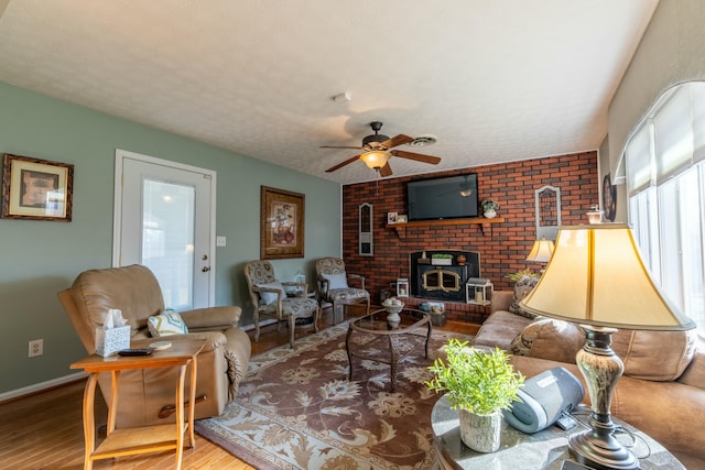 living room with a ceiling fan, a textured ceiling, baseboards, and wood finished floors