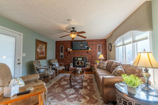 living area with a ceiling fan, a wood stove, a textured ceiling, and wood finished floors